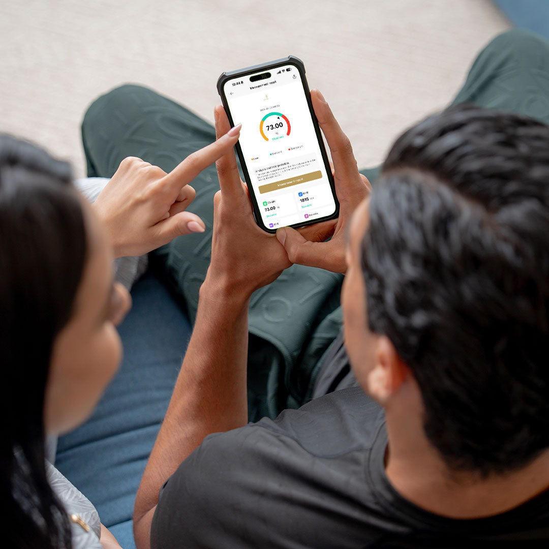 Two people looking at a smartphone screen with a fitness app displayed.