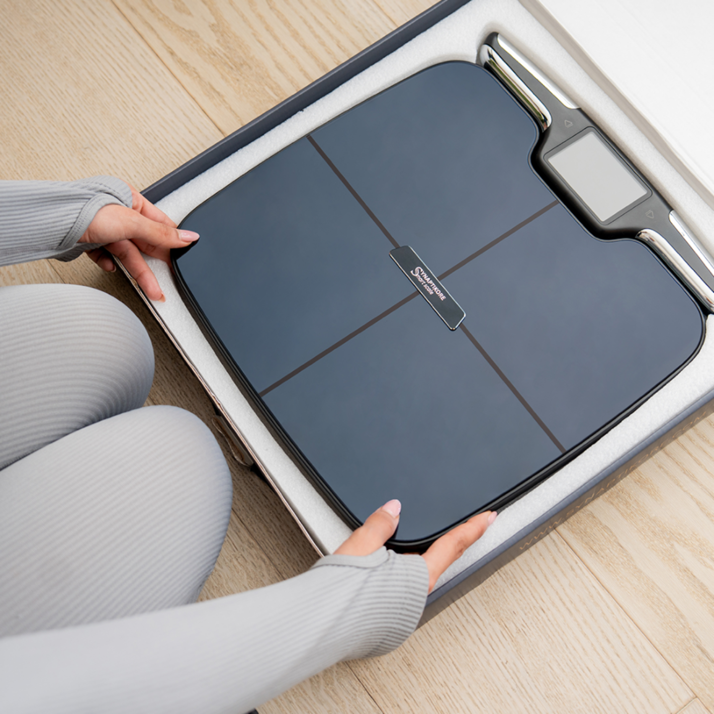 Person opening a smart scale with a focus on the brand logo.